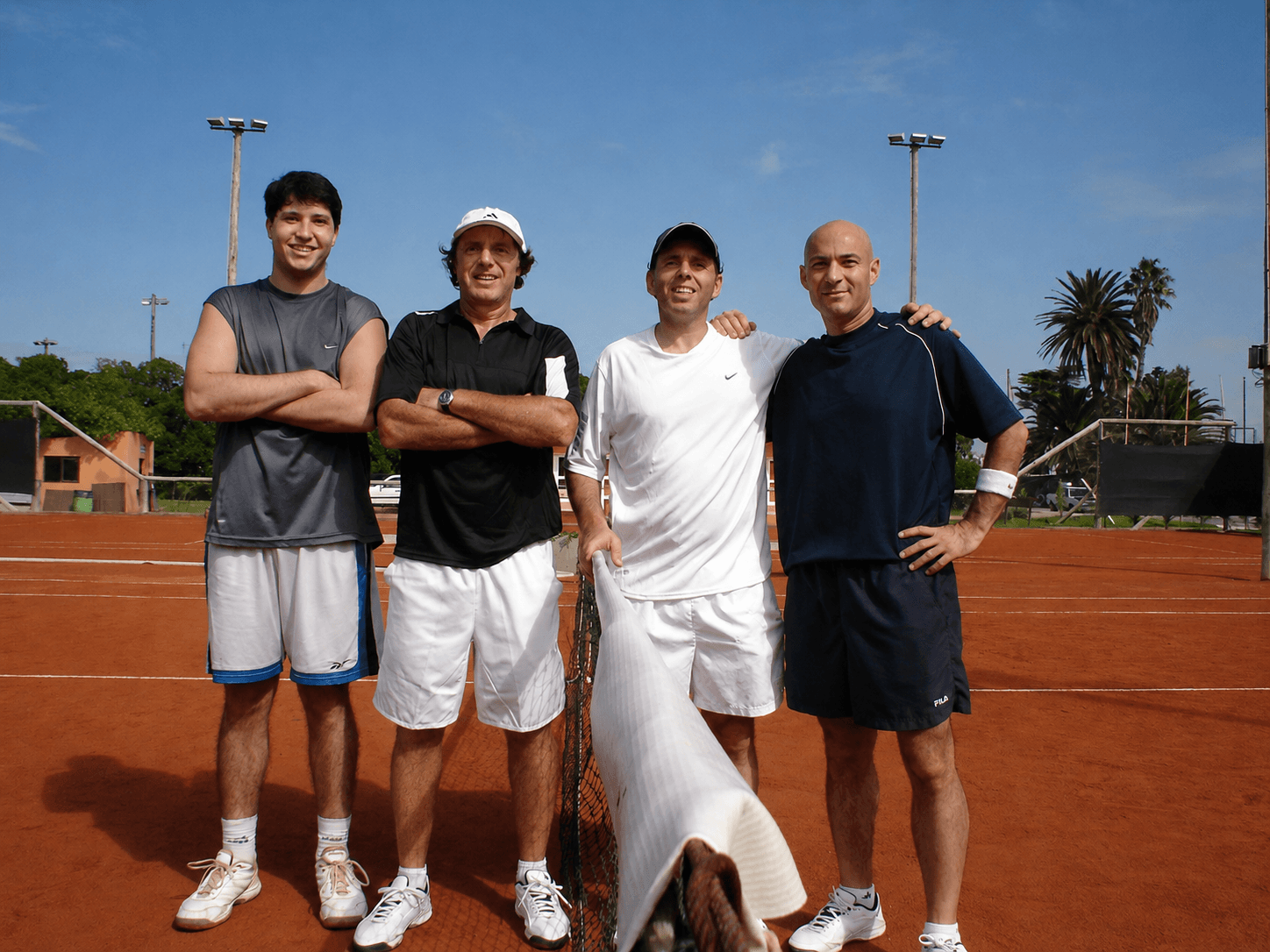Jorge Pensky standing with adult tennis players on court