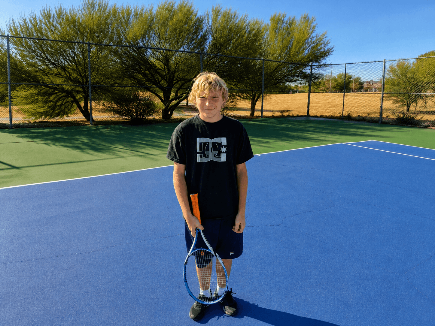 Jugador de tenis de high school de pie en la cancha